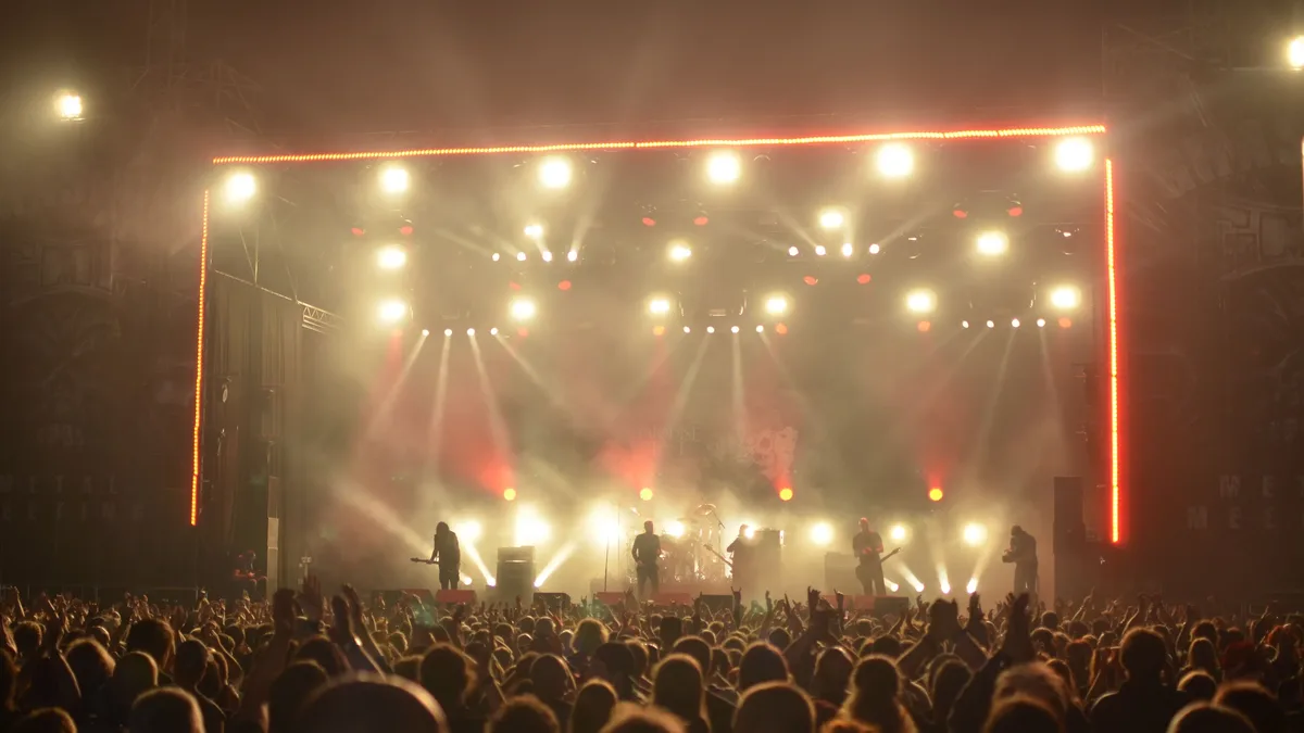 A concert scene with a stage, crowd, and stage lights.